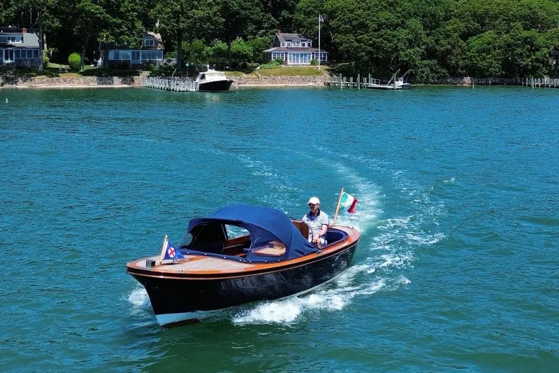 The Image of 2003 Castine Harbor Launch boat cruising on a scenic lake with lush shoreline. - 0