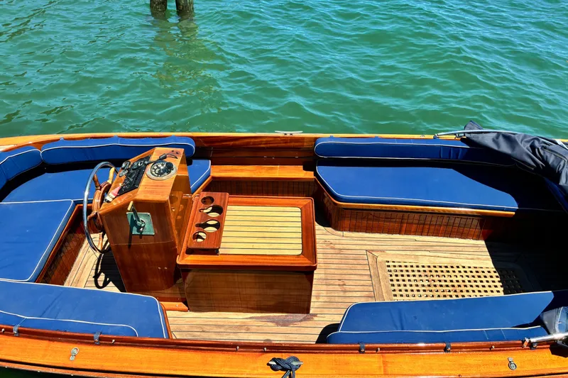 Slide: The Image of 2003 Castine Harbor Launch boat with wooden deck and blue seating on clear water. - 18