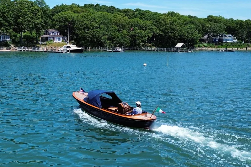 Slide: The Image of 2003 Castine Harbor Launch cruising on a serene lake with lush green shoreline. - 9