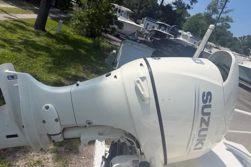 Slide: The Image of Suzuki outboard motor on a 2019 Carolina Skiff 218 DLV boat, parked outdoors. - 6