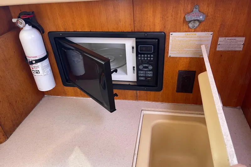 Slide: The Image of 2004 Hunter 33-2 yacht kitchen with microwave, fire extinguisher, and sink. - 16