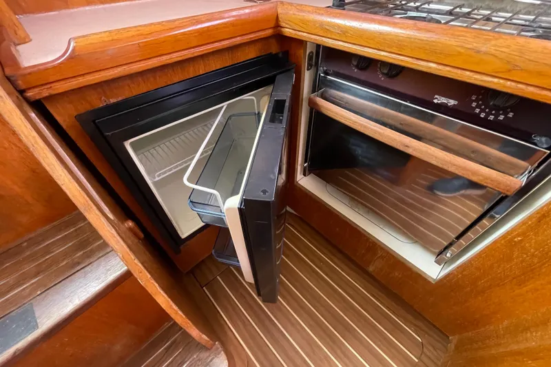 Slide: The Image of 2004 Hunter 33-2 yacht kitchen with open fridge and oven, wooden interior. - 17