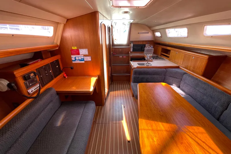 Slide: The Image of 2004 Hunter 33-2 yacht interior with wood finish, seating, and kitchenette. - 23
