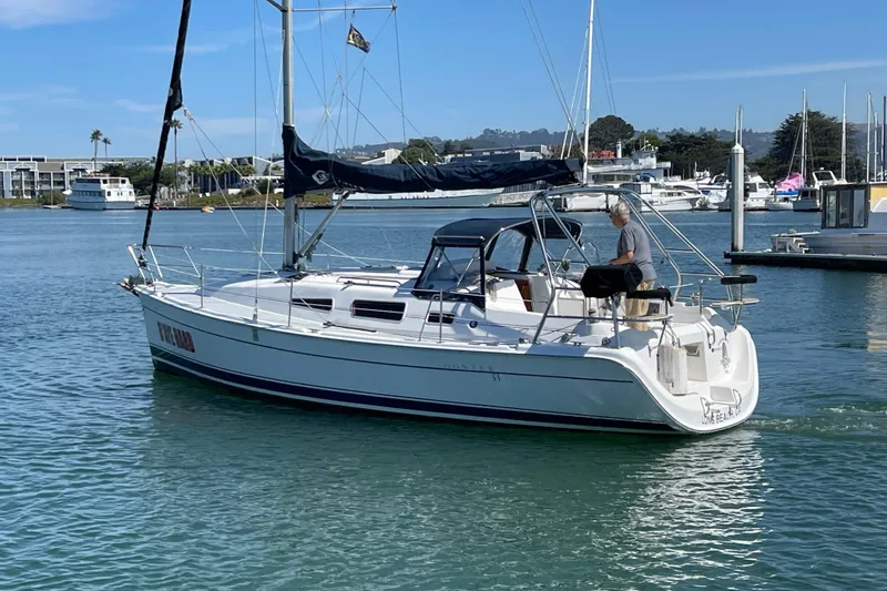 Slide: The Image of 2004 Hunter 33-2 sailboat cruising in a marina with a person on deck. - 5
