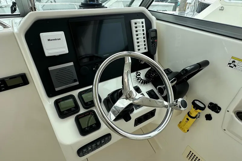 Slide: The Image of 2013 Glacier Bay 2680 Coastal Runner helm with steering wheel and navigation controls. - 7
