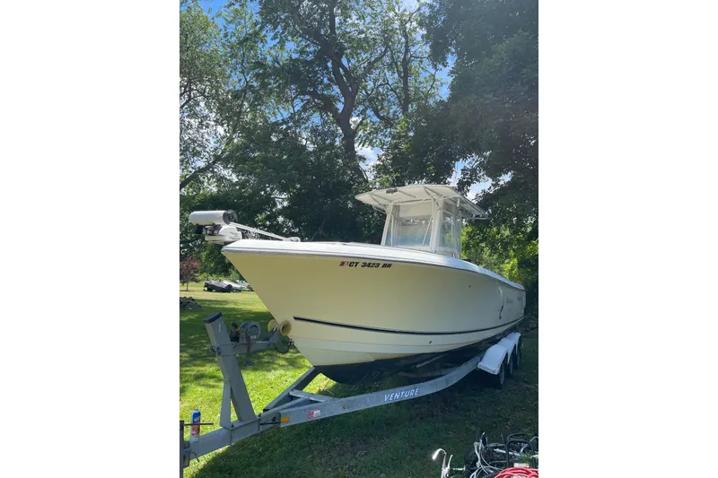 The Image of 2006 Sailfish 2660 CC boat on trailer, parked outdoors under trees. - 1