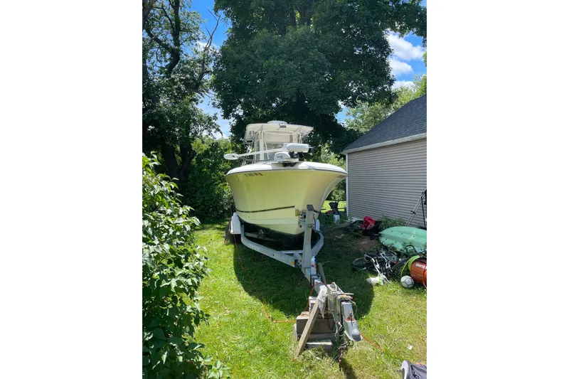 Slide: The Image of 2006 Sailfish 2660 CC boat on trailer, parked in a grassy yard. - 2