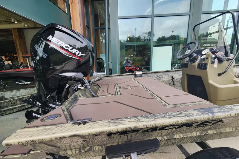 Slide: The Image of 2026 Tracker Grizzly 1860 CC boat with Mercury engine, displayed outdoors near a glass building. - 3