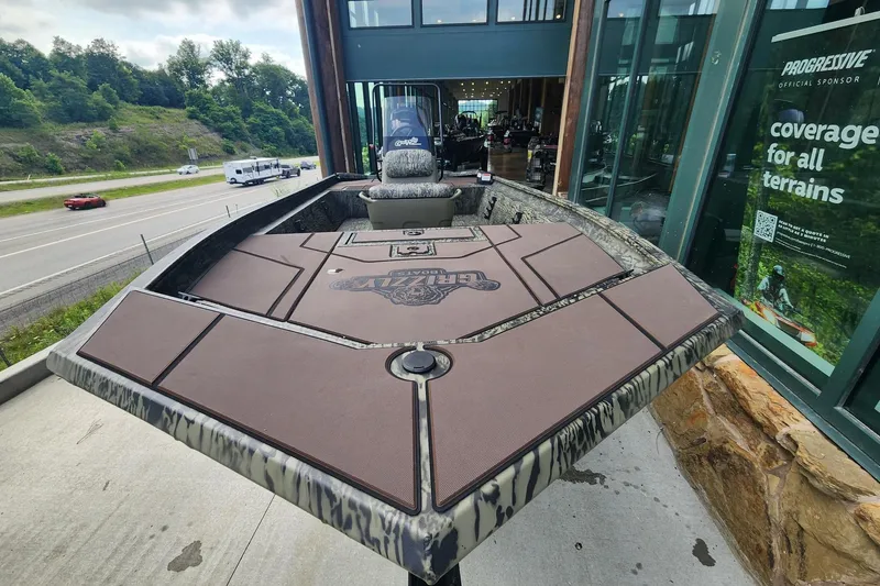 Slide: The Image of 2026 Tracker Grizzly 1860 CC boat displayed outdoors near a highway and storefront. - 4