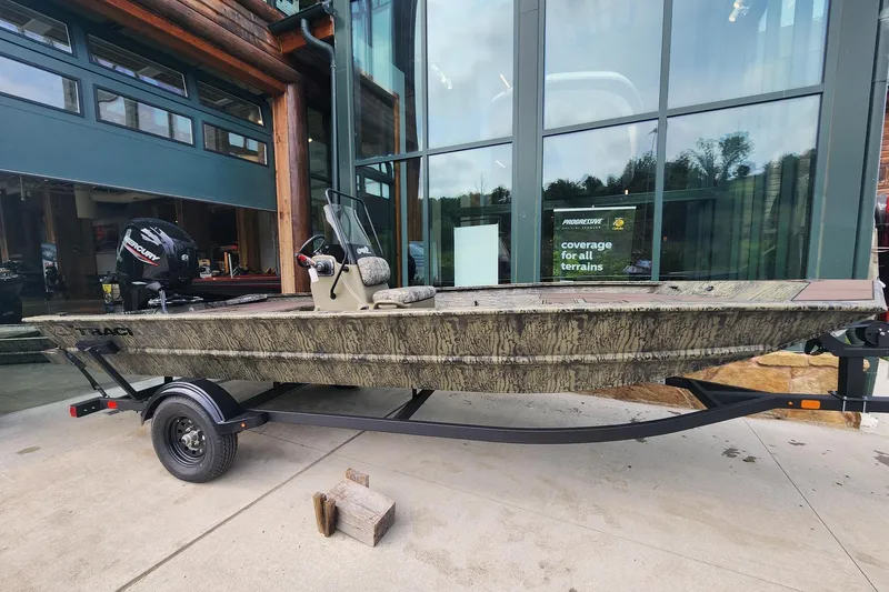 The Image of 2026 Tracker Grizzly 1860 CC boat on trailer, parked outside a modern building. - 0
