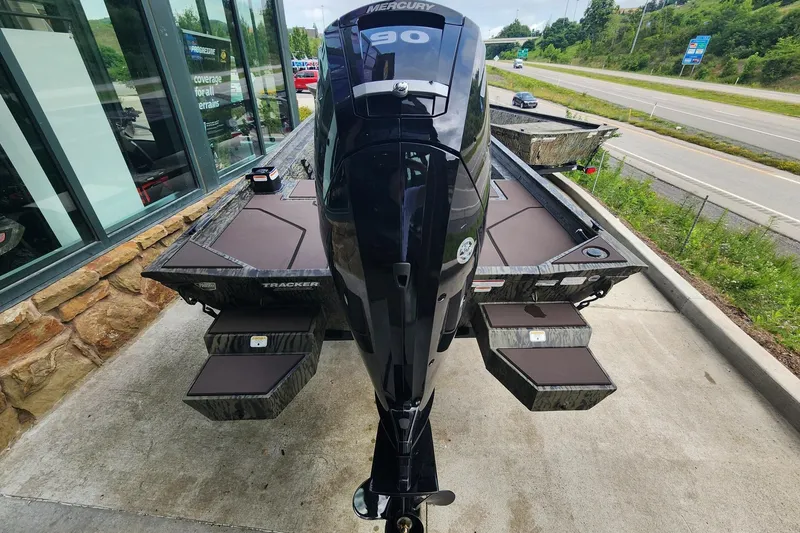 Slide: The Image of 2026 Tracker Grizzly 1860 CC boat with Mercury engine, parked near a highway. - 2