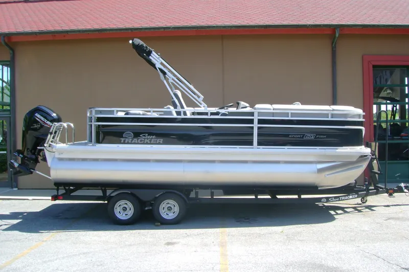 The Image of 2026 Sun Tracker SportFish 20 DLX pontoon boat on trailer, parked outdoors. - 0