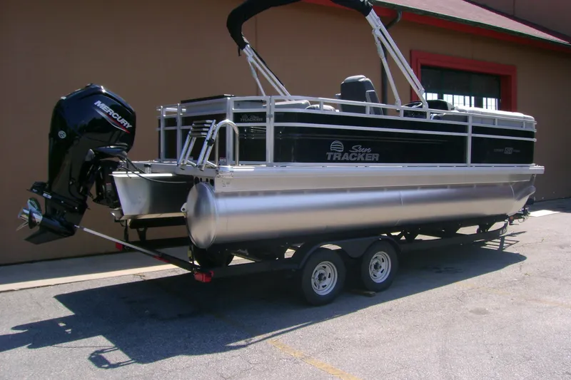 Slide: The Image of 2026 Sun Tracker SportFish 20 DLX pontoon boat on trailer, featuring Mercury outboard motor. - 2