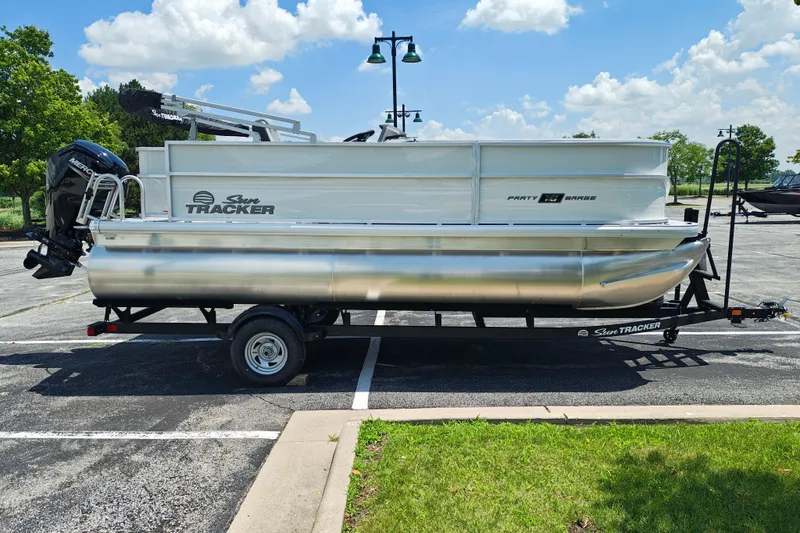 The Image of 2026 Sun Tracker Party Barge 18 DLX pontoon boat on trailer in parking lot. - 1
