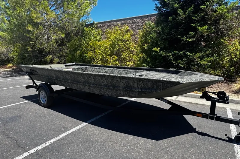 Slide: The Image of 2026 Tracker Grizzly 1860 Utility boat on trailer in sunny parking lot. - 2