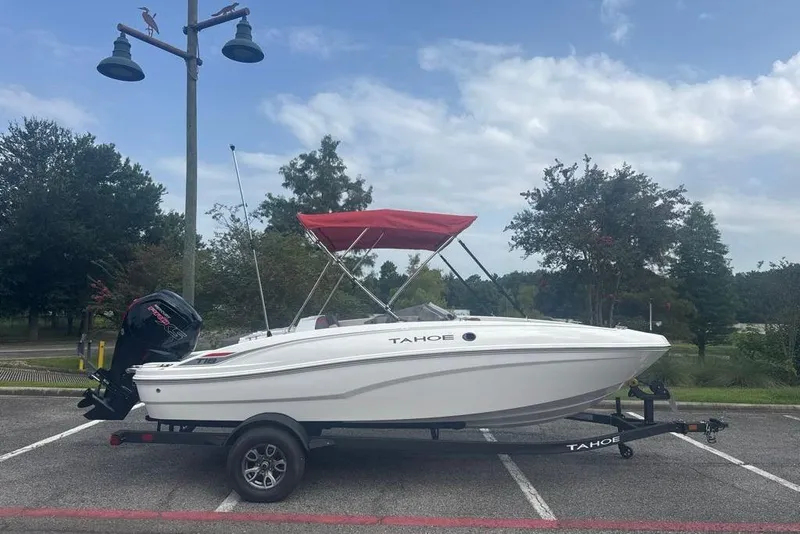 The Image of 2026 Tahoe T18 boat with red canopy on trailer in parking lot. - 0