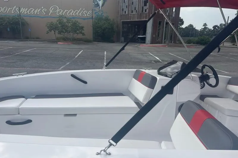 Slide: The Image of 2026 Tahoe T18 boat interior with red and gray seating, parked near "Sportsman's Paradise." - 7