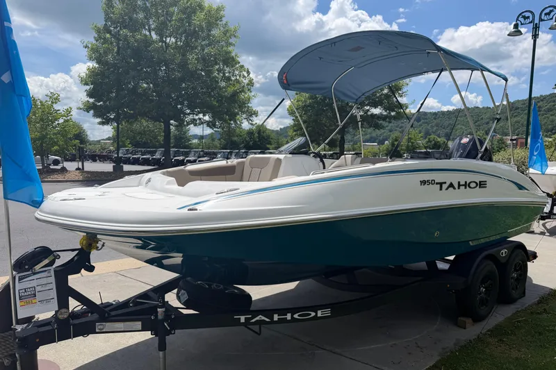 Slide: The Image of 2026 Tahoe 1950 boat with canopy on trailer, parked outdoors under a blue sky. - 1