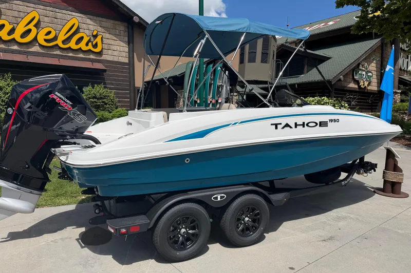 Slide: The Image of 2026 Tahoe 1950 boat with canopy and outboard motor, displayed outside Cabela's store. - 3
