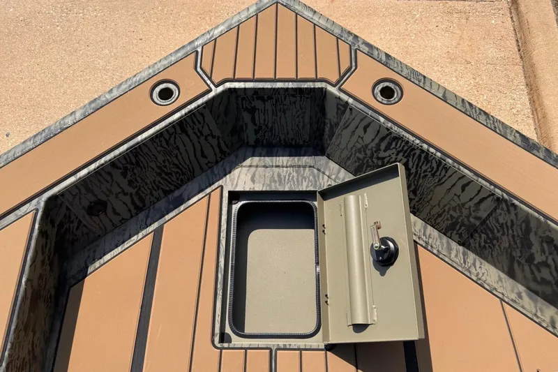 Slide: The Image of The image shows the bow of a Tracker Grizzly 1756 T Marsh boat with an open storage compartment. - 10