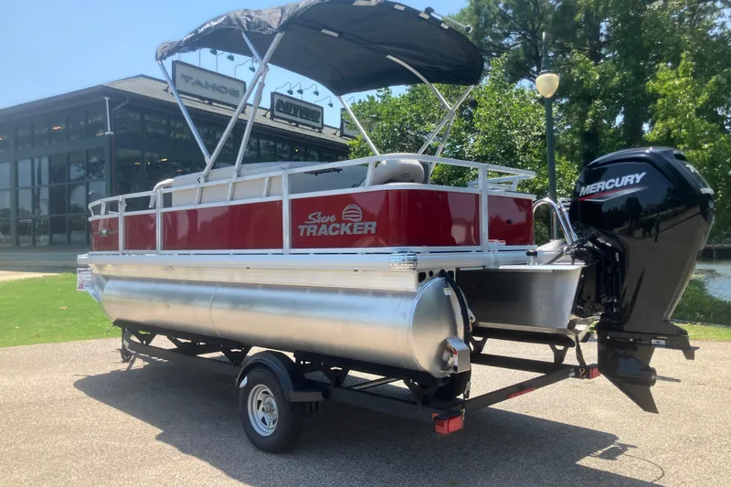 Slide: The Image of 2026 Sun Tracker Bass Buggy 18 DLX pontoon boat with Mercury engine, parked outdoors. - 3