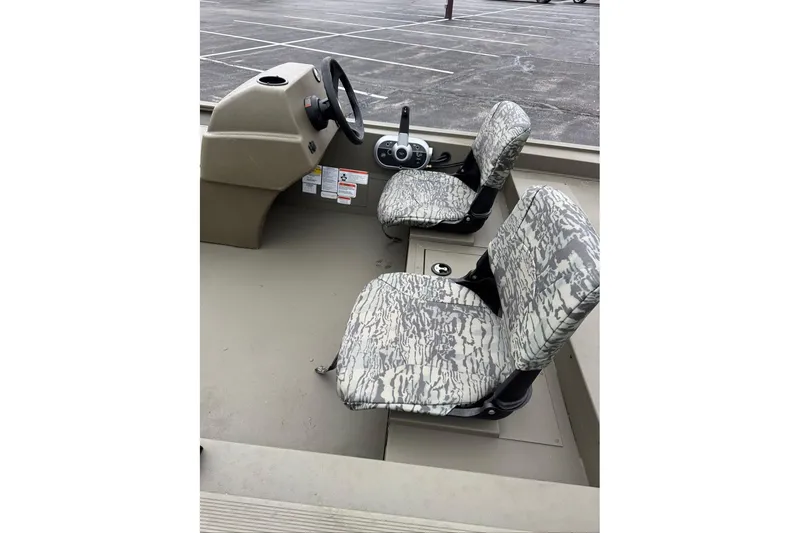 Slide: The Image of 2026 Tracker Grizzly 1754 SC boat interior with camo seats and steering console. - 7