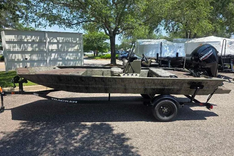 The Image of 2026 Tracker Grizzly 1860 CC boat on trailer, parked outdoors under trees. - 0