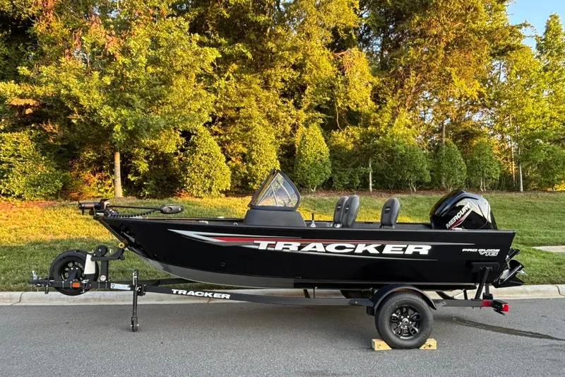 The Image of 2026 Tracker Pro Guide V-16 WT boat on trailer, parked on a road with trees in background. - 0
