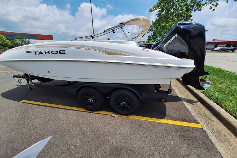 The Image of 2026 Tahoe 2150 boat on trailer in parking lot, featuring Mercury outboard motor. - 0
