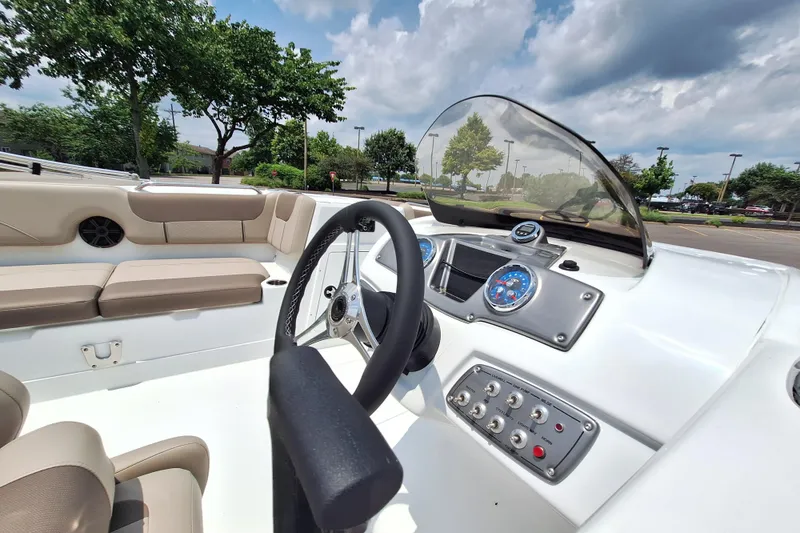 Slide: The Image of 2026 Tahoe 2150 boat interior with steering wheel, dashboard, and beige seating. - 4