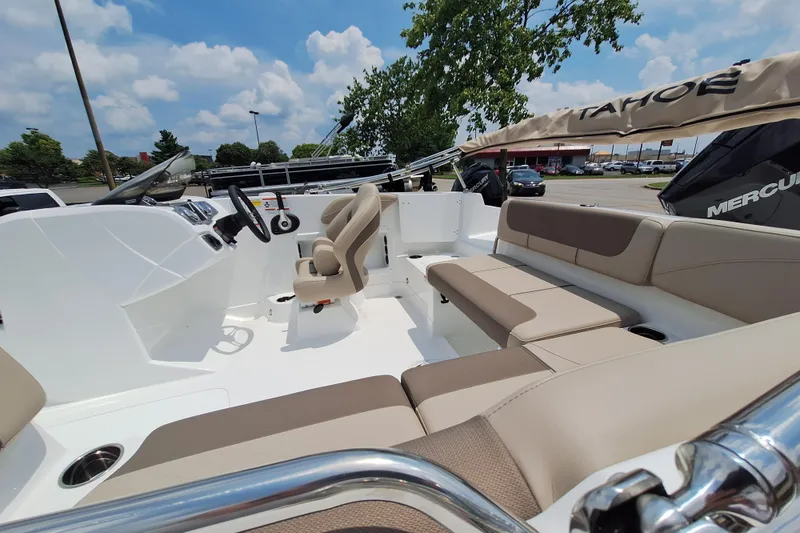 Slide: The Image of 2026 Tahoe 2150 boat interior with beige seating and steering wheel, under a clear blue sky. - 1