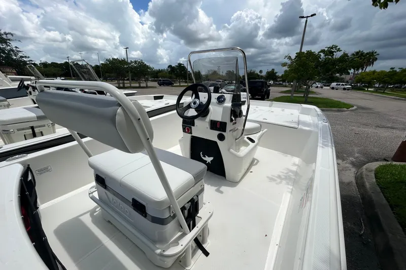 Slide: The Image of 2026 Mako Pro Skiff 17 CC boat interior with steering console and seating, parked outdoors. - 3