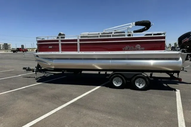 The Image of 2026 Sun Tracker SportFish 20 DLX pontoon boat on trailer in parking lot. - 0