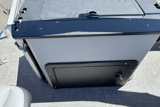 Slide: The Image of 2026 Sun Tracker SportFish 20 DLX boat storage compartment with black lid and latch. - 16