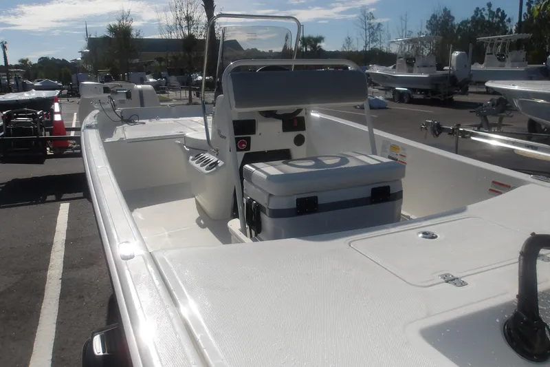 Slide: The Image of 2026 Mako Pro Skiff 17 CC boat with center console and seating, parked outdoors. - 17