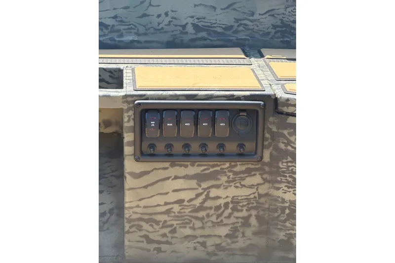 Slide: The Image of Control panel of 2026 Tracker Grizzly 1756 T Marsh boat with switches and camo design. - 7