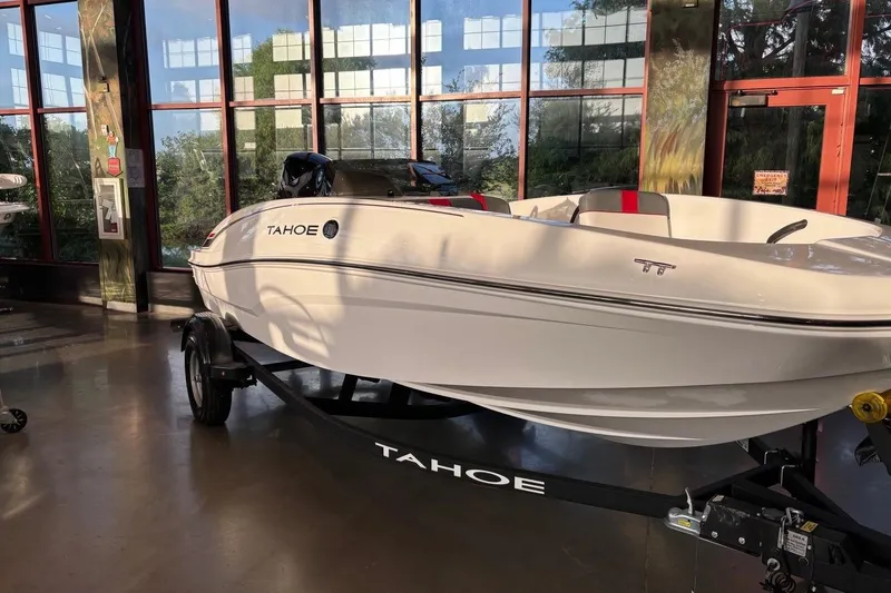 Slide: The Image of 2026 Tahoe T16 boat displayed indoors on a trailer, with sleek white design. - 3