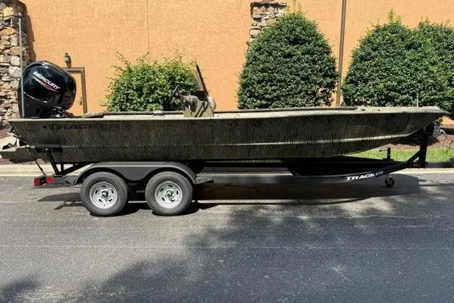 The Image of 2026 Tracker Grizzly 2072 CC boat on trailer, parked outdoors, with Mercury engine. - 0