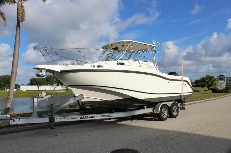 The Image of 2005 Boston Whaler 255 Conquest boat on trailer, parked near a scenic waterway. - 0