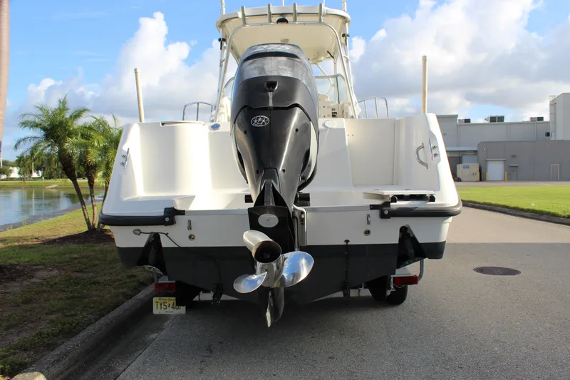 Slide: The Image of 2005 Boston Whaler 255 Conquest boat with outboard motor, parked near water. - 17