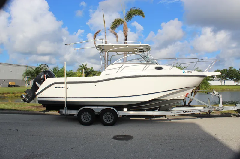 Slide: The Image of 2005 Boston Whaler 255 Conquest boat on trailer, parked near water, under blue sky. - 19