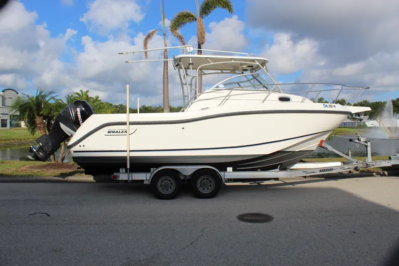 Slide: The Image of 2005 Boston Whaler 255 Conquest boat on trailer, parked near palm trees and water. - 20