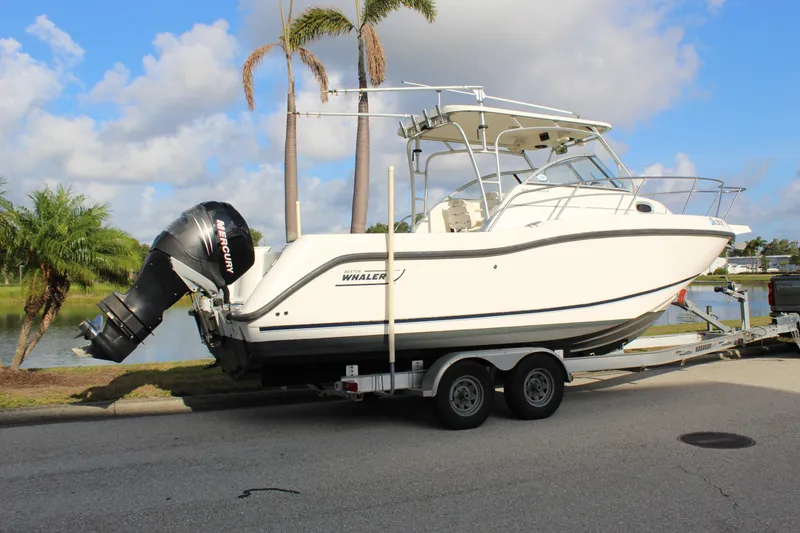 Slide: The Image of 2005 Boston Whaler 255 Conquest boat on trailer, parked near palm trees and water. - 21