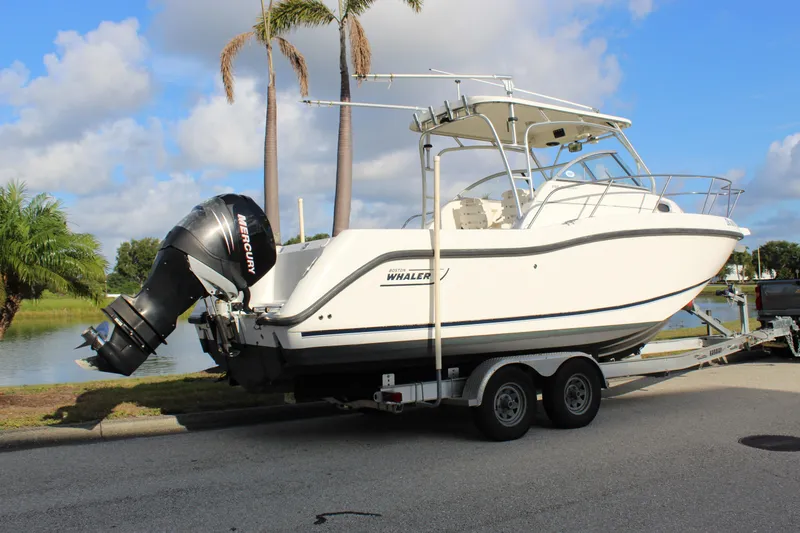 Slide: The Image of 2005 Boston Whaler 255 Conquest boat on trailer, parked near palm trees and water. - 22