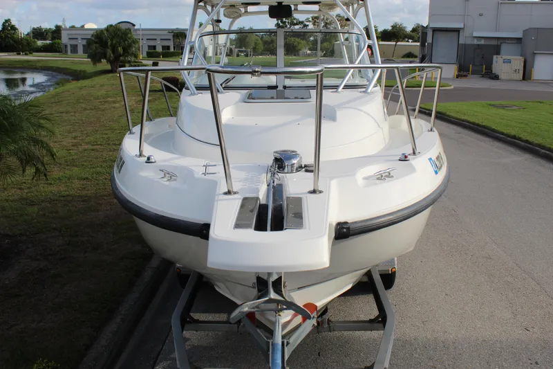Slide: The Image of 2005 Boston Whaler 255 Conquest boat on trailer, parked near a pond and industrial buildings. - 26