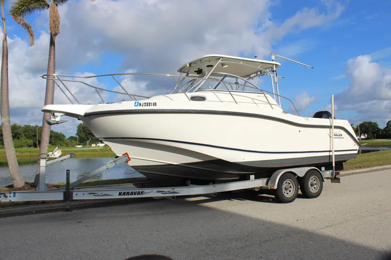 Slide: The Image of 2005 Boston Whaler 255 Conquest boat on trailer, parked near palm trees and water. - 3