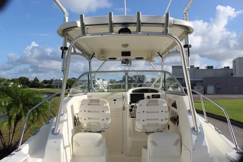Slide: The Image of 2005 Boston Whaler 255 Conquest boat interior with helm and seating, under clear blue sky. - 30
