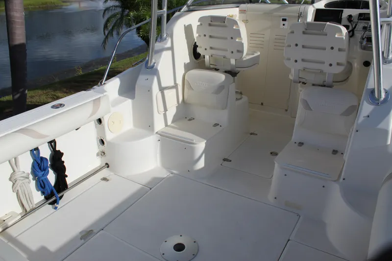 Slide: The Image of 2005 Boston Whaler 255 Conquest boat interior with seating and storage, docked by a lake. - 34