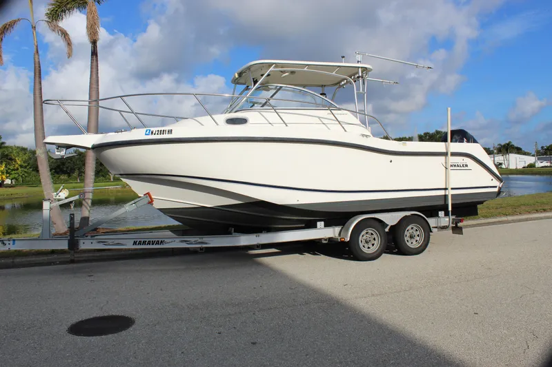 Slide: The Image of 2005 Boston Whaler 255 Conquest boat on trailer, parked near a scenic waterway. - 4