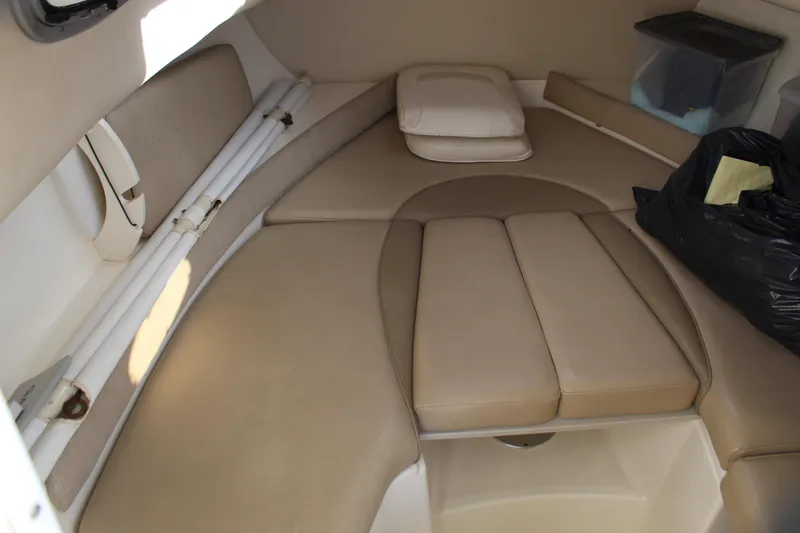 Slide: The Image of 2005 Boston Whaler 255 Conquest cabin interior with beige cushions and storage items. - 42